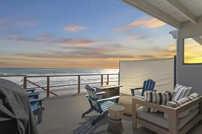 a balcony with chairs and a desk and the ocean at Private beach toes on the Sand Waterworld in Dana Point