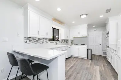 a kitchen with white cabinets and a large white island at Sleeps 31 10br Mountain View, Pool, Spa and Games in El Cajon