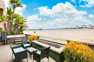 a patio with a table and chairs and the beach at Beachfront Bliss Cozy 1BR Condo with Shared Perks in San Diego