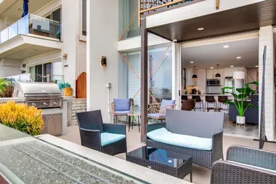 an outdoor patio with chairs and a grill at Beachfront Bliss Cozy 1BR Condo with Shared Perks in San Diego