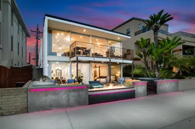 a large house with a sunset in the background at Beachfront Bliss Cozy 1BR Condo with Shared Perks in San Diego