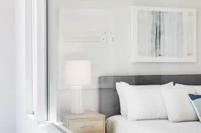 a bed with a lamp on a night stand next to a window at Bayfront Beauty 3BR Mission Bay Retreat in San Diego