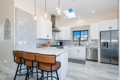 a kitchen with white cabinets and a island with bar stools at Inviting 3BR Space with Firepit in San Clemente