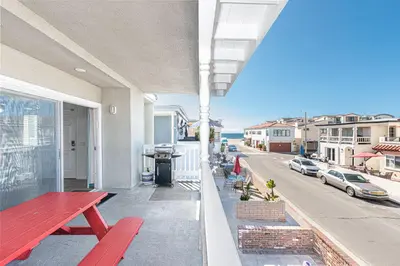 a balcony with a red bench and a street at 4Br Coastal Home W Oceanview Patio, Close To The Beach By Beachview Rentals in Newport Beach