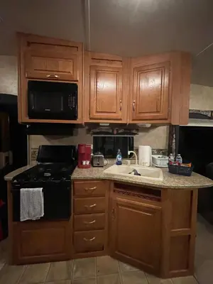 a kitchen with wooden cabinets and a stove and a sink at La Mesa Cozy Camper in San Diego