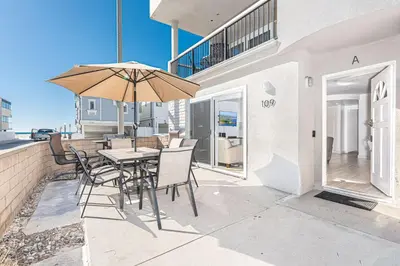 a patio with a table and chairs and an umbrella at 3Br Oceanview Corner Retreat One House From The Beach By Beachview Rentals in Newport Beach