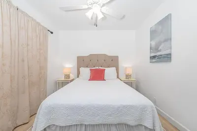 a bedroom with a white bed with a red pillow at 3Br Oceanview Corner Retreat One House From The Beach By Beachview Rentals in Newport Beach