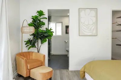 a bedroom with a bed and a chair and a plant at SD Lux Oasis: Theatre, Spa, 14Beds, AC, Sleeps 20+ in Spring Valley
