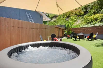 a hot tub in a yard with an umbrella at Sunnyside Resort Spa, Beach, Zoo, Arcade in La Mesa