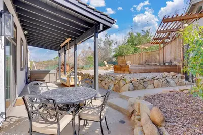 a patio with a table and chairs and a stone wall at Secluded Oasis: Pickleball, Jacuzzi, Pool, & Views in Lakeside