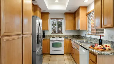 a kitchen with wooden cabinets and white appliances at Walk to Dining Mission Pacific Beach and BarsNightlife Private Backyard in San Diego