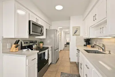 a kitchen with white cabinets and stainless steel appliances at Seize the Day in San Diego