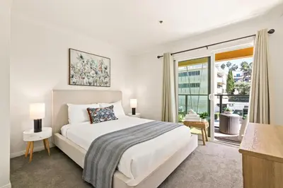 a white bedroom with a bed and a large window at Seize the Day in San Diego