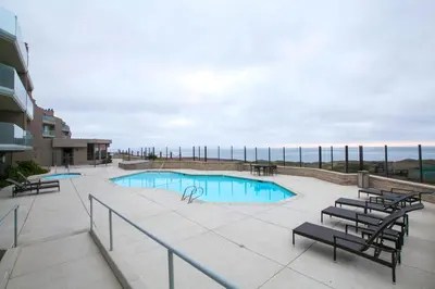 a swimming pool with chairs and a patio at Surf Song Symphony - SONG55 in Solana Beach
