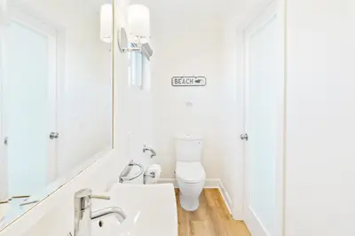 a white bathroom with a toilet and a mirror at Coastal Escape Ping Pong Bikes and Steps to Sand in San Diego