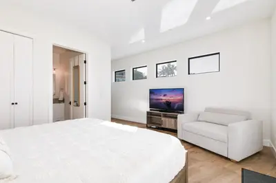 a white bedroom with a bed and a chair at Luxury Pool Haven Scenic Views and Summer Fireworks in San Diego