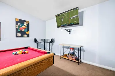 a room with a bed and a football game on a tv at Serene Sanctuary Pool, Hot Tub and Game Room in San Diego
