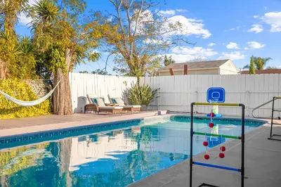 a swimming pool with a swing next to a fence at Serene Sanctuary Pool, Hot Tub and Game Room in San Diego