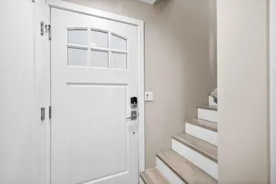 a white door in a hallway with stairs at Ocean Breeze and Rooftop Views Steps to Surf and Sun in San Diego