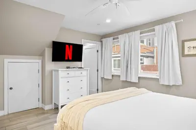 a bedroom with a white bed and a tv at Ocean Breeze and Rooftop Views Steps to Surf and Sun in San Diego