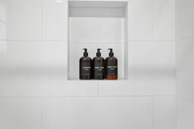 three bottles of wine in a white cabinet at Ocean Breeze and Rooftop Views Steps to Surf and Sun in San Diego