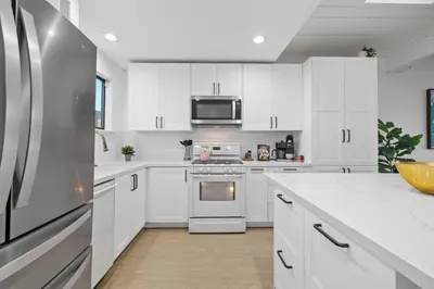 a kitchen with white cabinets and a stainless steel refrigerator at Modern Pacific Beach Retreat with Hot Tub and Views in San Diego