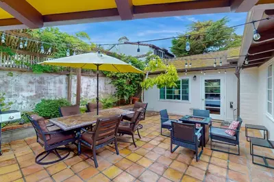 a patio with a table and chairs and an umbrella at La Jolla Historic Gem, Hot Tub, Game Room, Garden Oasis with Firepit & Courtyard Dining in San Diego