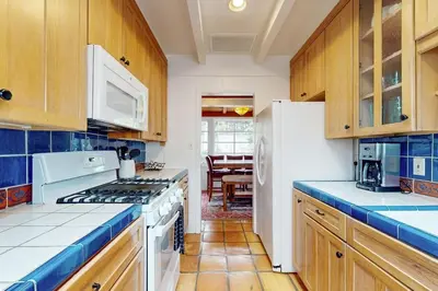 a kitchen with wooden cabinets and a white stove top oven at La Jolla Historic Gem, Hot Tub, Game Room, Garden Oasis with Firepit & Courtyard Dining in San Diego