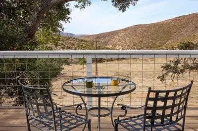 a glass table and two chairs on a balcony at 320 Acres Farmhouse in East County San Diego