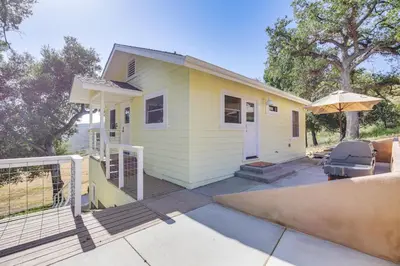 a small yellow house with a porch and an umbrella at 320 Acres Farmhouse in East County San Diego