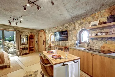 a kitchen with stone walls and a island with a table at Casa Grotto in San Marcos