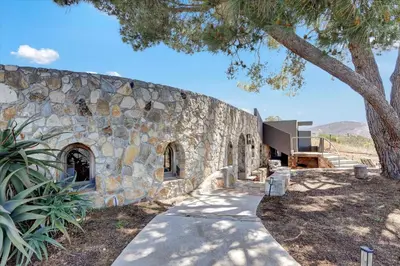 a stone building with a tree next to a sidewalk at Casa Grotto in San Marcos