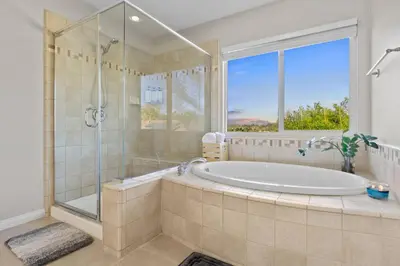 a bathroom with a tub and a shower and a window at Sunset Crest - Home with stunning views, Pool, BBQ in Fallbrook