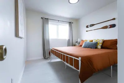 a bedroom with a bed with orange sheets and a window at King Suite - 2min Walk to Beach Close to Downtown! in Oceanside