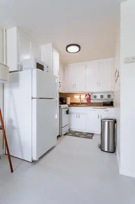 a kitchen with white cabinets and a white refrigerator at King Suite - 2min Walk to Beach Close to Downtown! in Oceanside