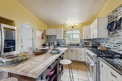 a kitchen with white cabinets and a wooden counter top at Seabreeze Bungalow in Oceanside