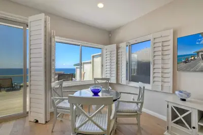 a dining room with a table and chairs and windows at Beachfront Sunset in Encinitas