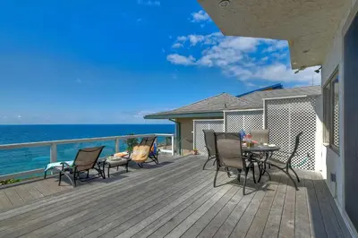 a deck with chairs and a table and the ocean at Beachfront Sunset in Encinitas