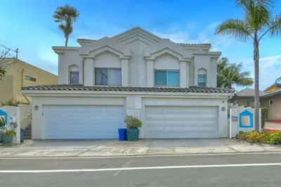 a house with two garage doors in front of a street at Beachfront Sunset in Encinitas