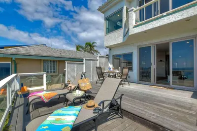a deck with chairs and tables on a house at Beachfront Sunset in Encinitas