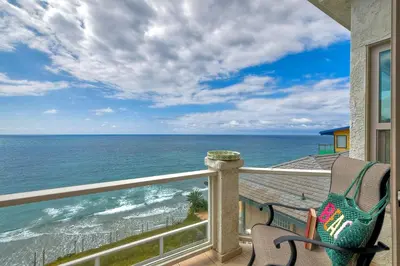 a balcony with a chair looking out at the ocean at Beachfront Sunset in Encinitas