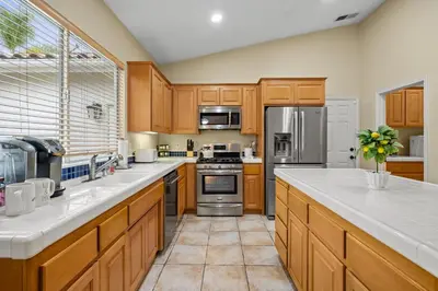 a large kitchen with wooden cabinets and stainless steel appliances at Explore Ramonas Vineyards Tranquil Home with Yard in Ramona