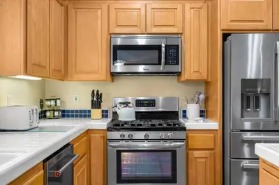 a kitchen with stainless steel appliances and wooden cabinets at Explore Ramonas Vineyards Tranquil Home with Yard in Ramona