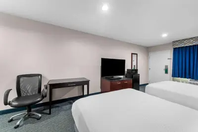 a hotel room with two beds and a desk and a chair at Quality Inn San Diego South - Chula Vista in Chula Vista