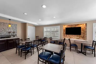 a restaurant with tables and chairs and a flat screen tv at Quality Inn San Diego South - Chula Vista in Chula Vista