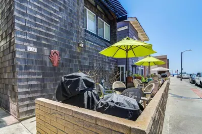 a row of tables and chairs with umbrellas on a sidewalk at Retro 3Br With Oceanview Patio In A Very Walkable Location By Beachview Rentals in Newport Beach