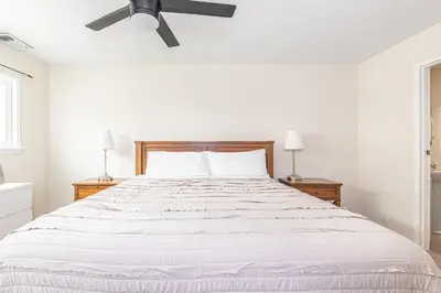 a white bedroom with a large bed with a ceiling fan at Pet-Friendly 3Br Retreat One House From The Sand By Beachview Rentals in Newport Beach