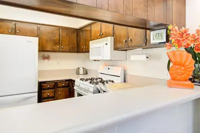 a kitchen with wooden cabinets and a white stove top oven at Retro 3Br Split-Level W Oceanview Patio Steps To Sand By Beachview Rentals in Newport Beach