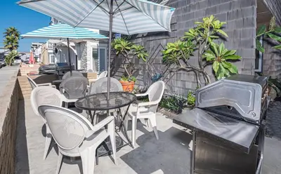 a patio with a table and chairs and a grill at Retro 3Br Split-Level W Oceanview Patio Steps To Sand By Beachview Rentals in Newport Beach