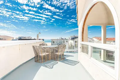 a patio with a table and chairs on a balcony at Oceanview Corner Home W Rooftop Deck, One House From Beach By Beachview Rentals in Newport Beach